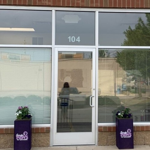 The Strictly Paws storefront at Unit 104, with purple flower planters flanking the front door
